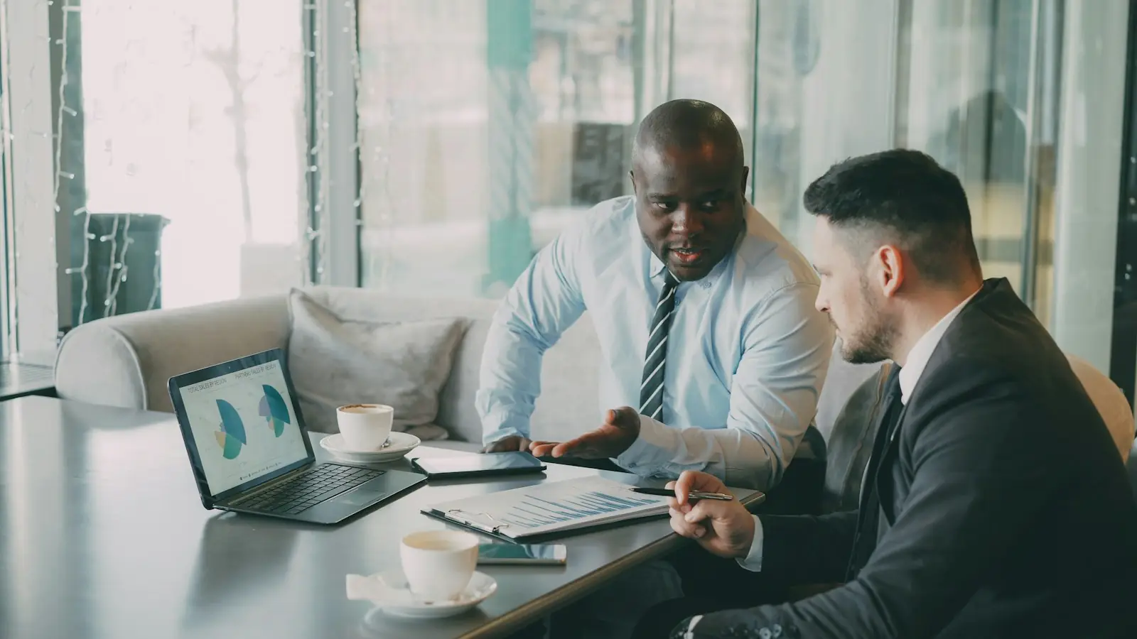 Two colleagues discussing charts on a laptop
